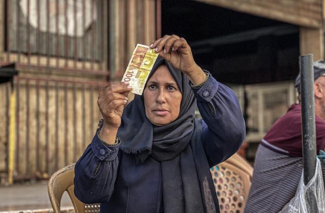 بالغراء والصبر… فلسطينية تُعيد الحياة للأوراق النقدية الممزقة في أسواق غزة المحاصرة